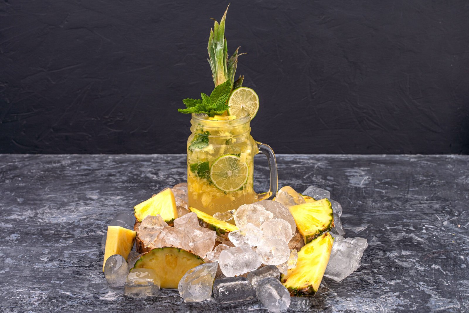 Close-up of a refreshing citrus and pineapple drink with ice, lemon, and mint leaves.